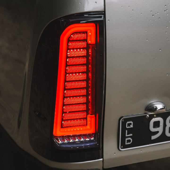 Close-up of a vehicle's tail light and license plate on a dark background